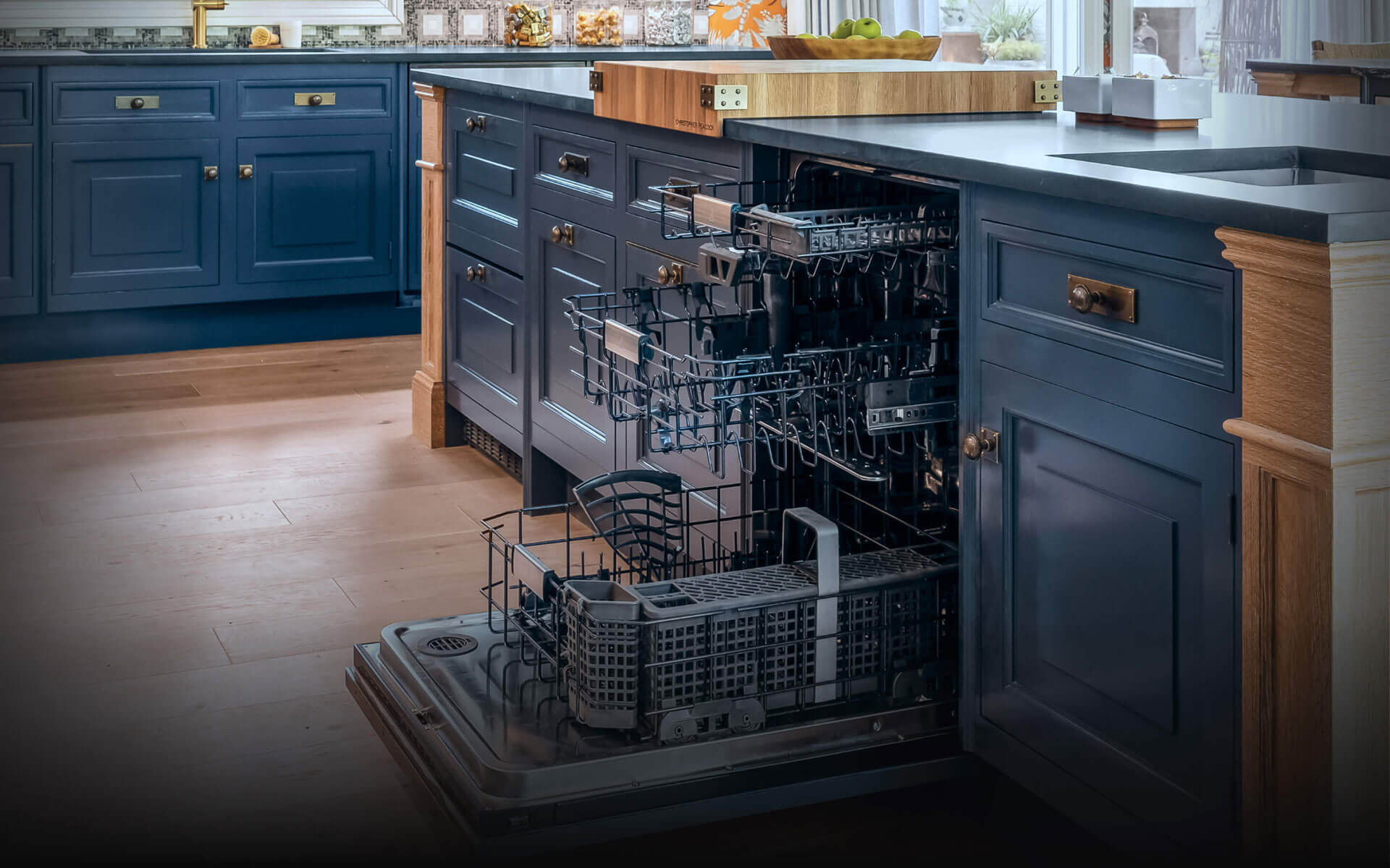 An open JennAir® Panel-Ready Dishwasher in a kitchen with blue cabinets. An open JennAir® Panel-Ready Dishwasher in a kitchen with blue cabinets.