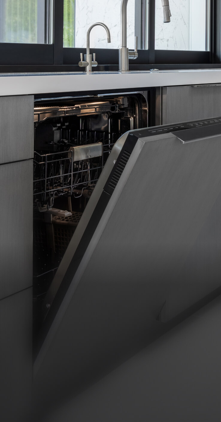 A JennAir® Panel-Ready Dishwasher with its door slightly ajar in a kitchen with gray cabinets. A JennAir® Panel-Ready Dishwasher with its door slightly ajar in a kitchen with gray cabinets.