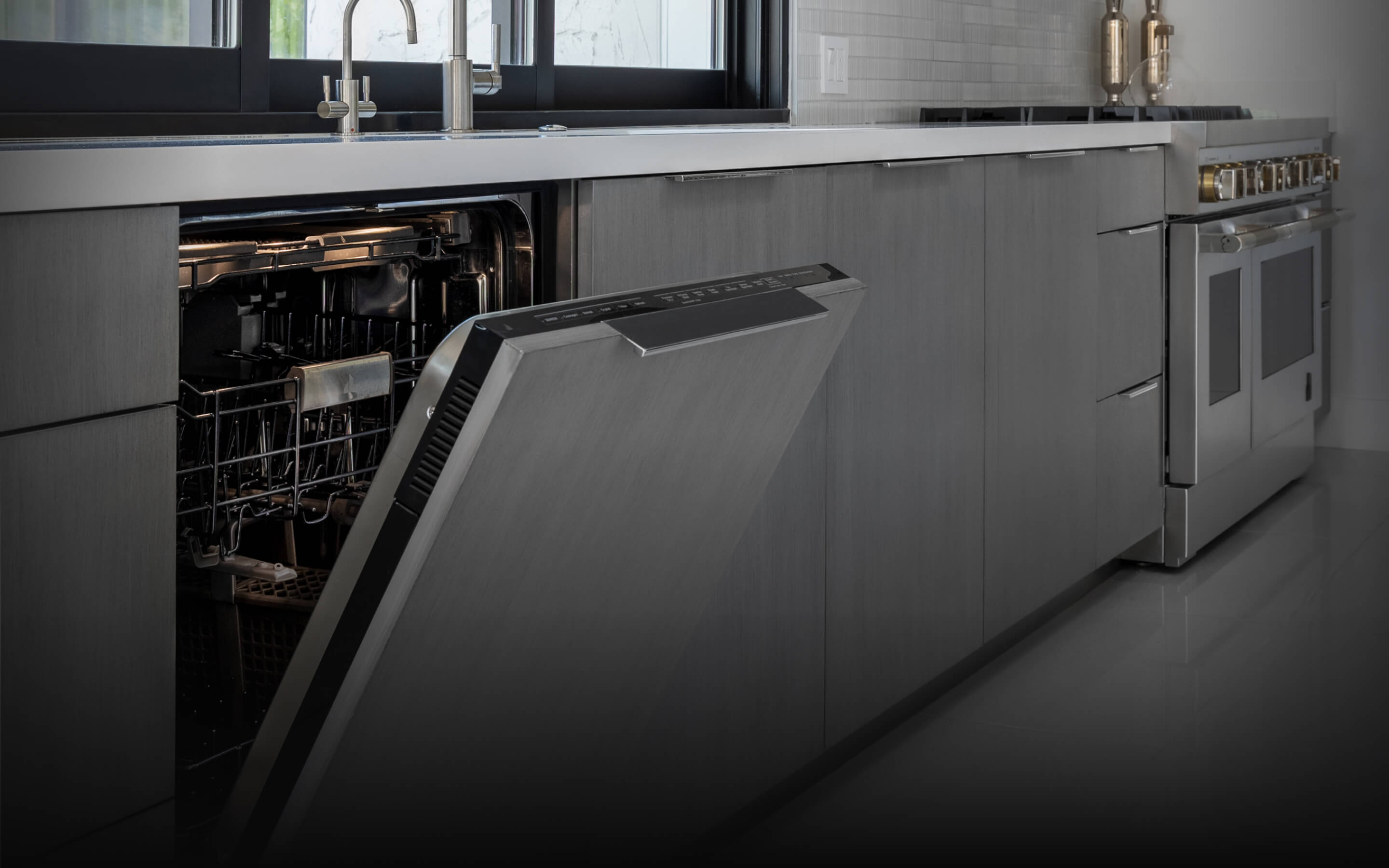 A JennAir® Panel-Ready Dishwasher with its door slightly ajar in a kitchen with gray cabinets. A JennAir® Panel-Ready Dishwasher with its door slightly ajar in a kitchen with gray cabinets.