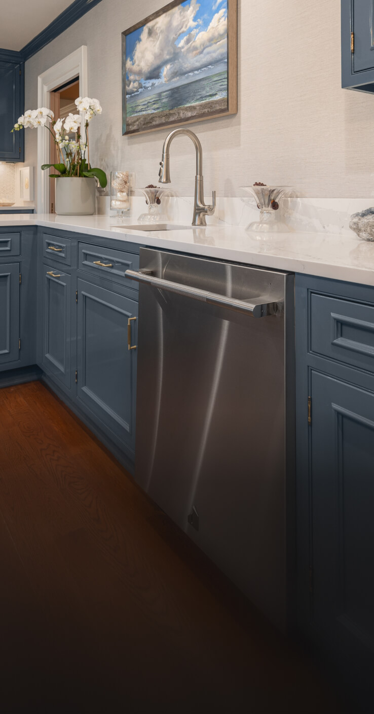 A JennAir® RISE™ Dishwasher in a kitchen with blue cabinets. A JennAir® RISE™ Dishwasher in a kitchen with blue cabinets.