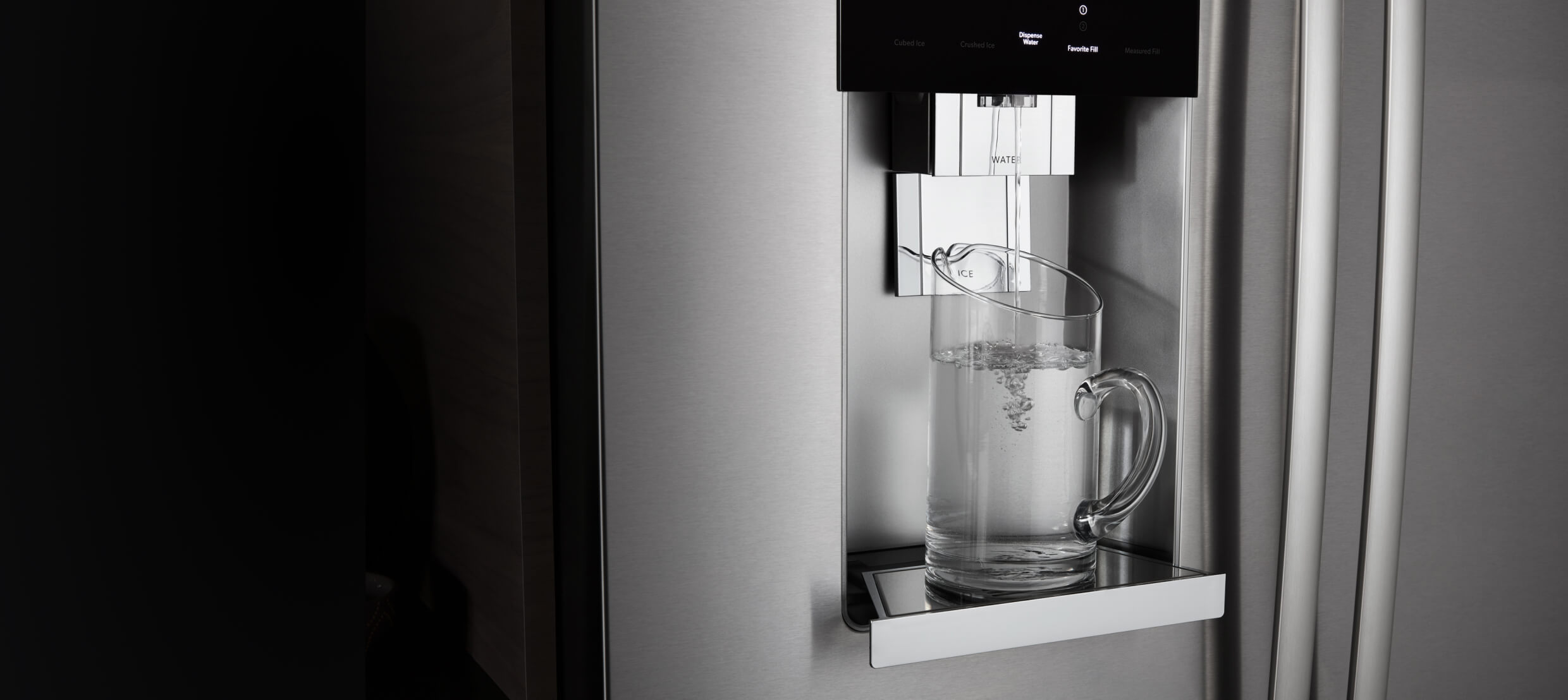 The front of a JennAir® built-in refrigerator, showing water being poured into a glass from the external dispenser.  The front of a JennAir® built-in refrigerator, showing water being poured into a glass from the external dispenser.