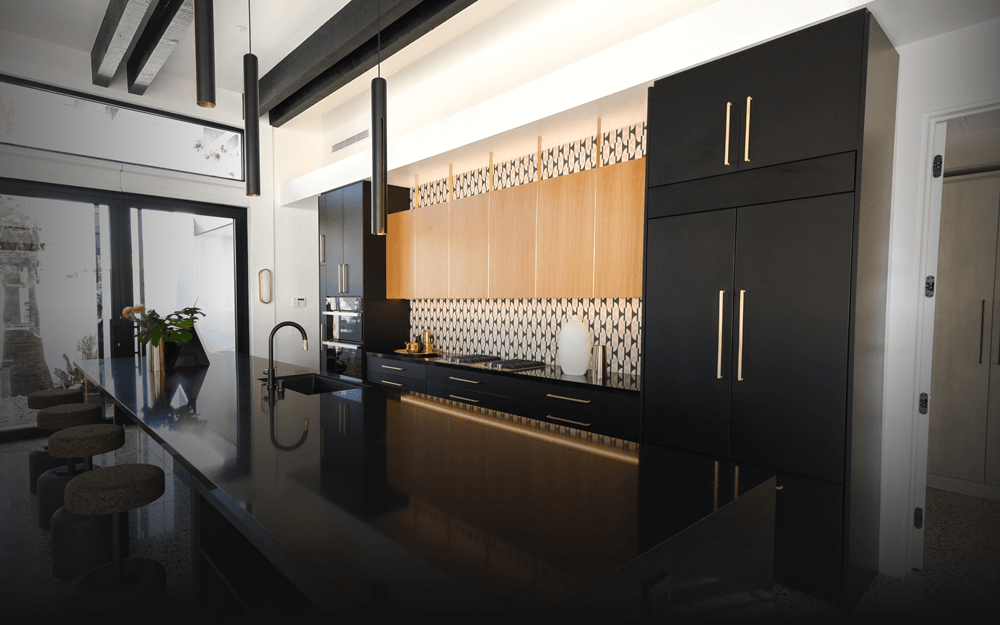 A black and gold modern kitchen featuring JennAir® appliances.  A black and gold modern kitchen featuring JennAir® appliances.