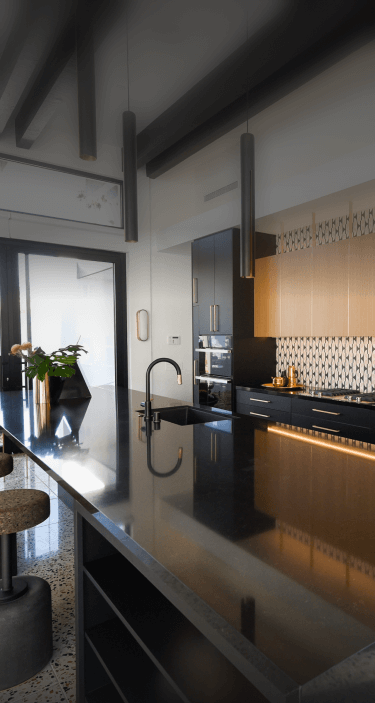 A black and gold modern kitchen featuring JennAir® appliances. A black and gold modern kitchen featuring JennAir® appliances.