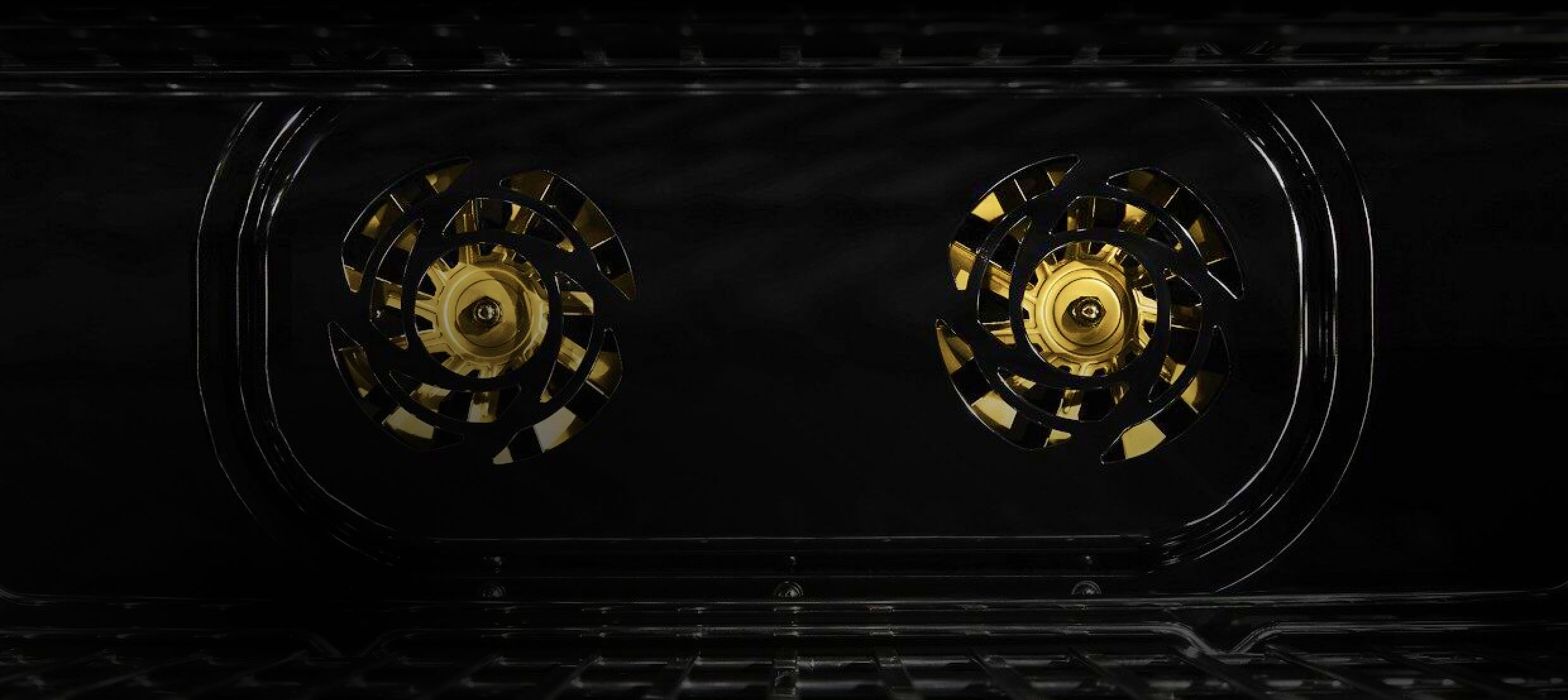 The interior of a JennAir® Professional-Style Range, with two brass fans.