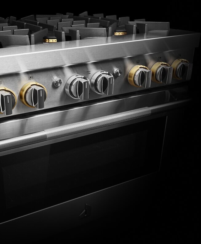 The top half of a JennAir® RISE™ Design Expression Professional-Style Range, showing the brass details on the knobs and burners.