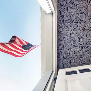 The wallpapered ceiling of the hallway showing an American flag outside of the front door.